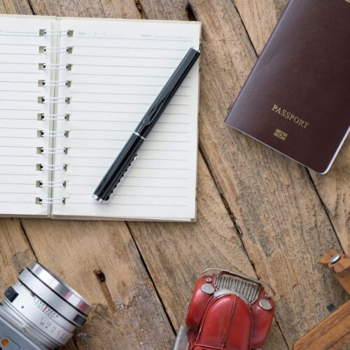 Passeport, carnet de notes et appareil photo posés sur une table en bois avant un départ en Tanzanie