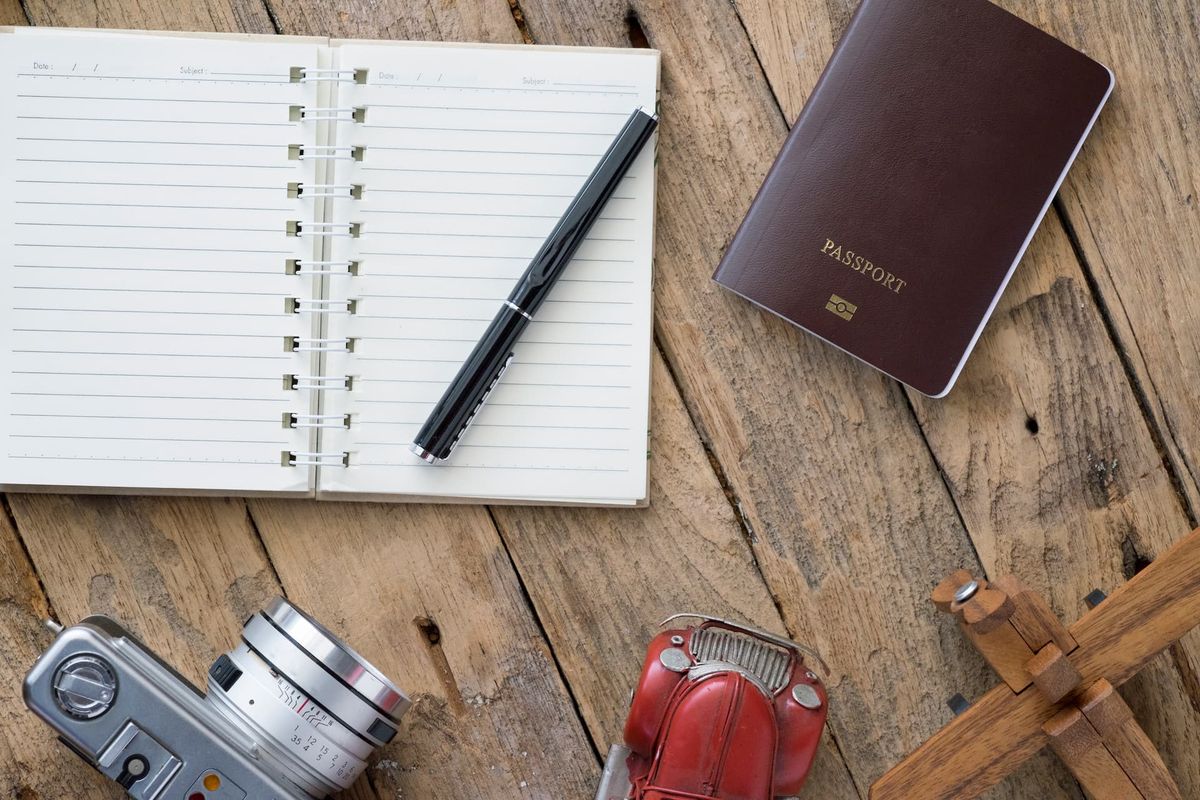 Passeport, carnet de notes et appareil photo posés sur une table en bois avant un départ en Tanzanie