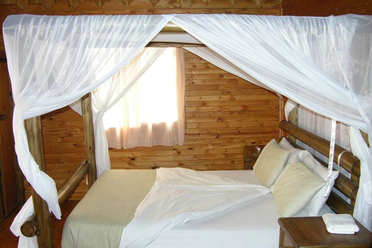 Lit sous moustiquaire dans une chambre de lodge en Tanzanie, à la tombée du jour